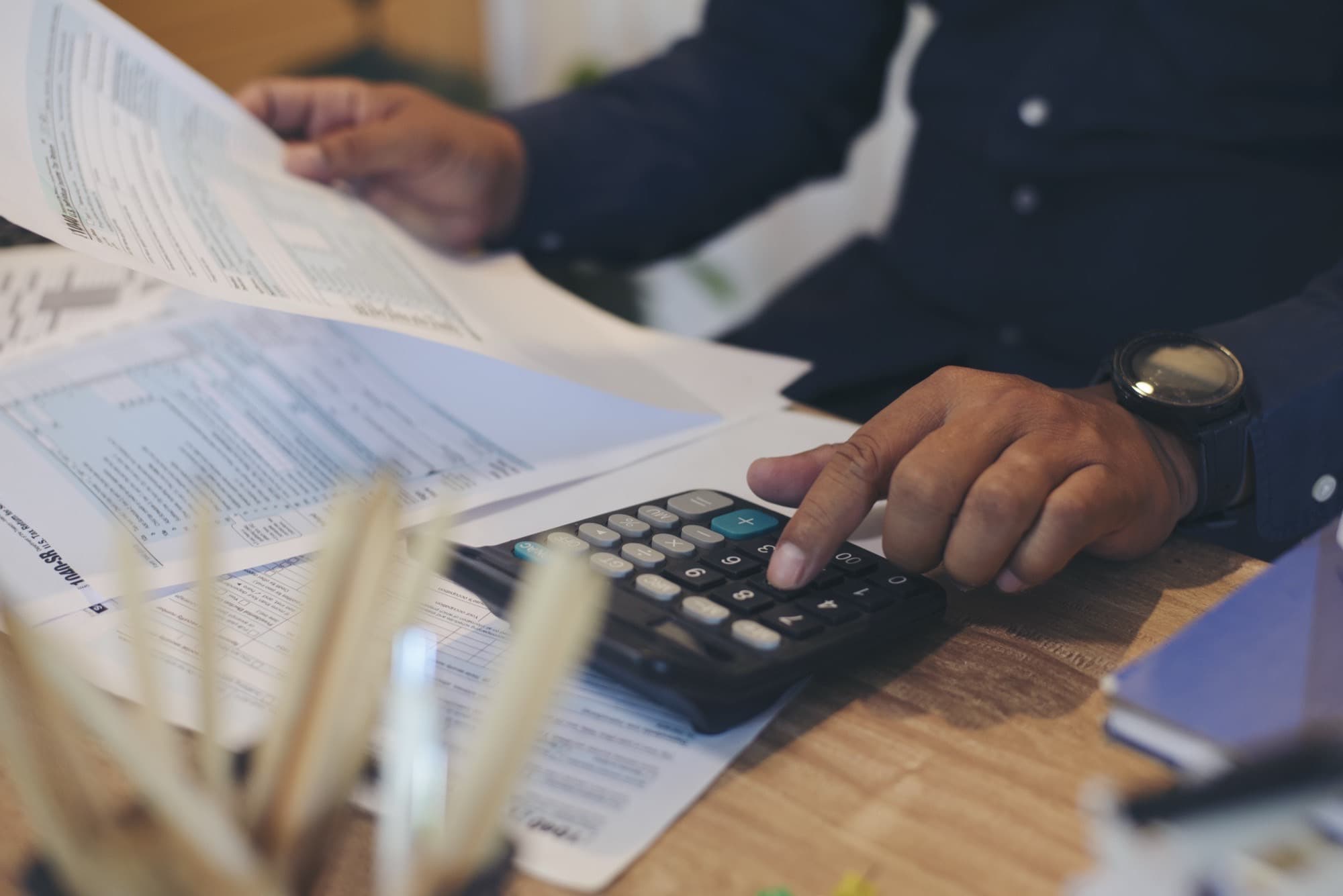 Calculating annual savings with a calculator and budget paperwork